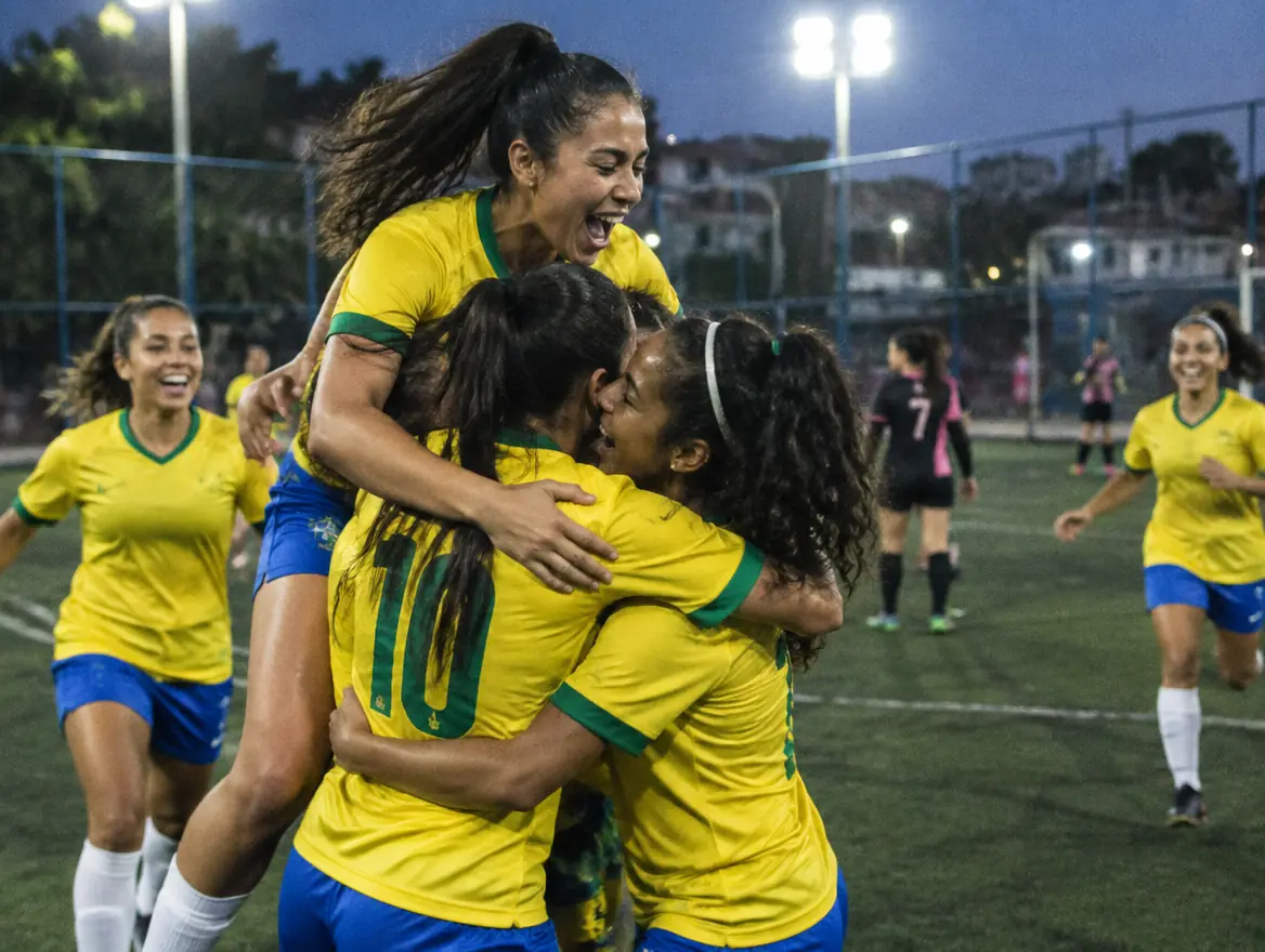 Time feminino comemorando gol abraçado na quadra de society